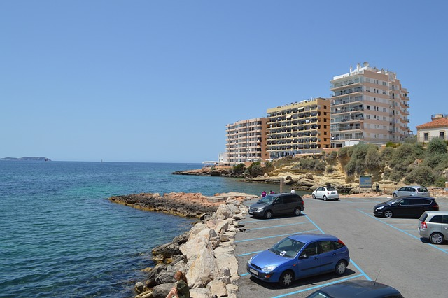 San Antonio, Ibiza, Hotels, Cars in parking lot, Blue sea with cliffs