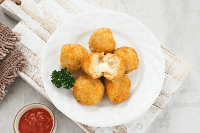 Spanish croquetas in a white bowl with salad.