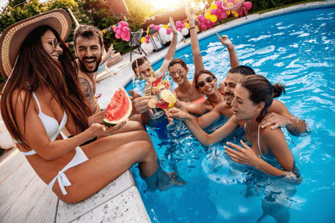pool party with women and men in a pool drinking cocktails and eating watermelons