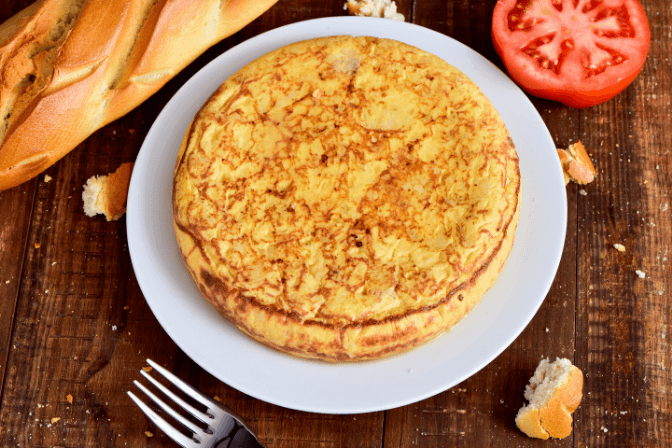 spanish omelette with fork and white plate.