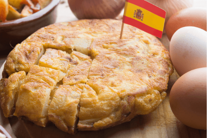 Tortilla de patatas bravas with a Spanish flag stuck in the middle of it.