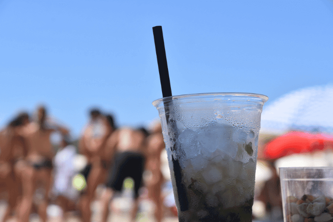 alcoholic drink on the beach with people standing behind it