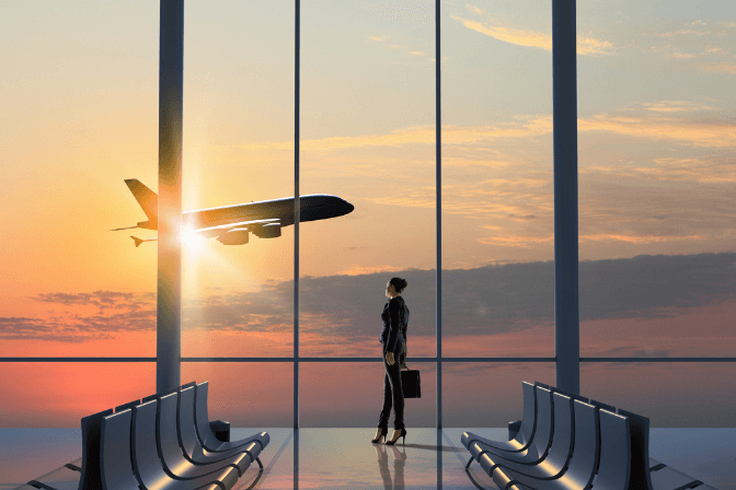 lady in airport watching plane take off in sunset