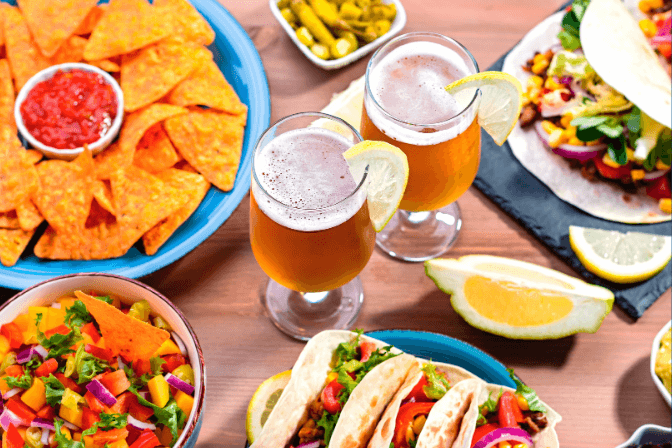 nachos and beer on a table with other food