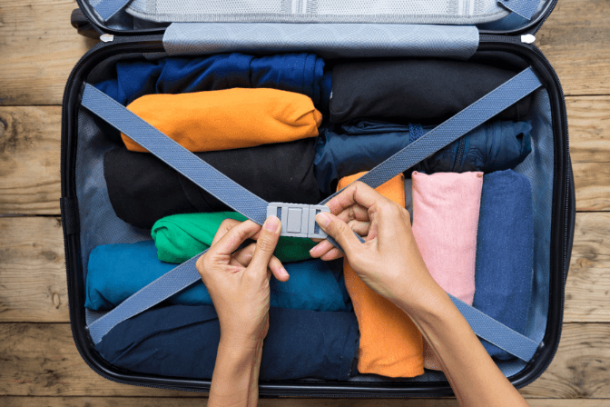 person packing luggage with clothes
