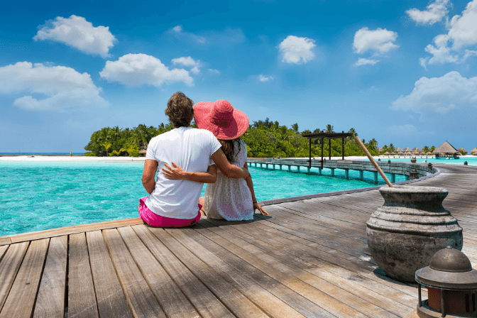 a man and woman embracing on a wooden platform in the maldives.