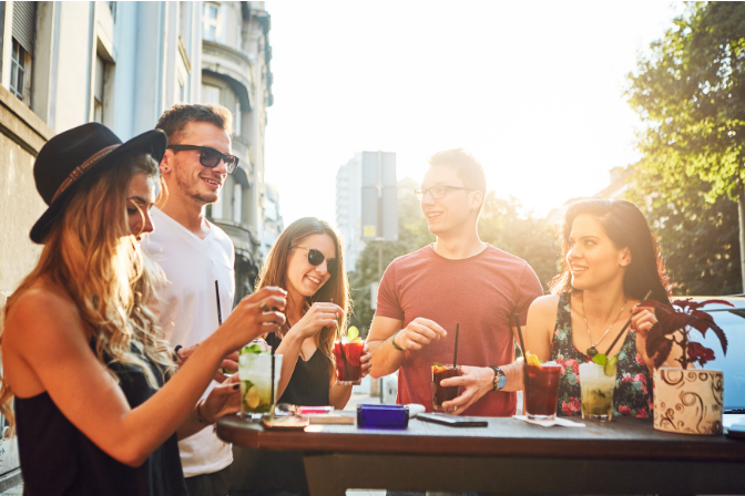 people drinking cocktails in a big city as a group.